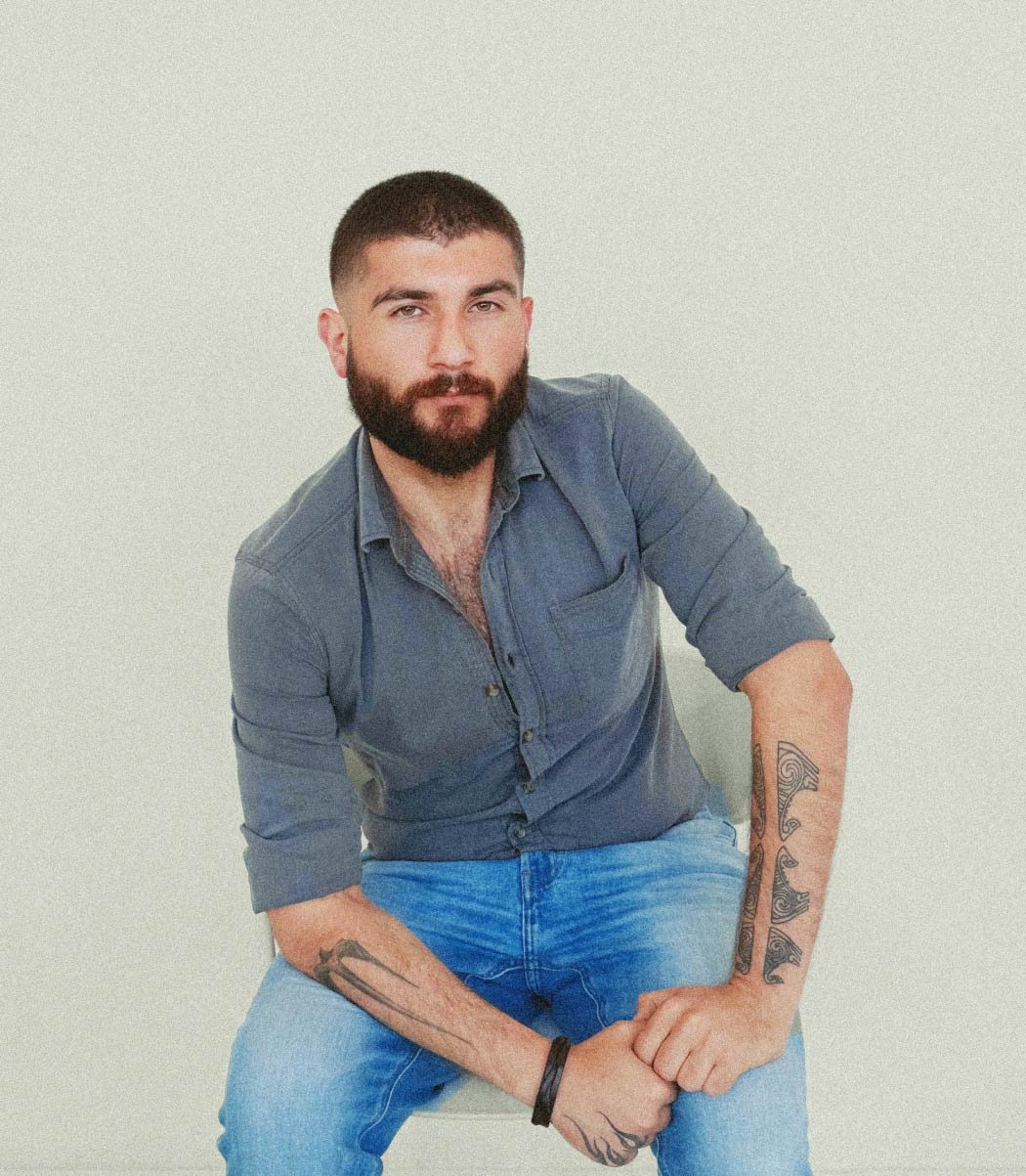 A man with a beard and short hair sits slightly leaning forward - portrait of Hovhannes.